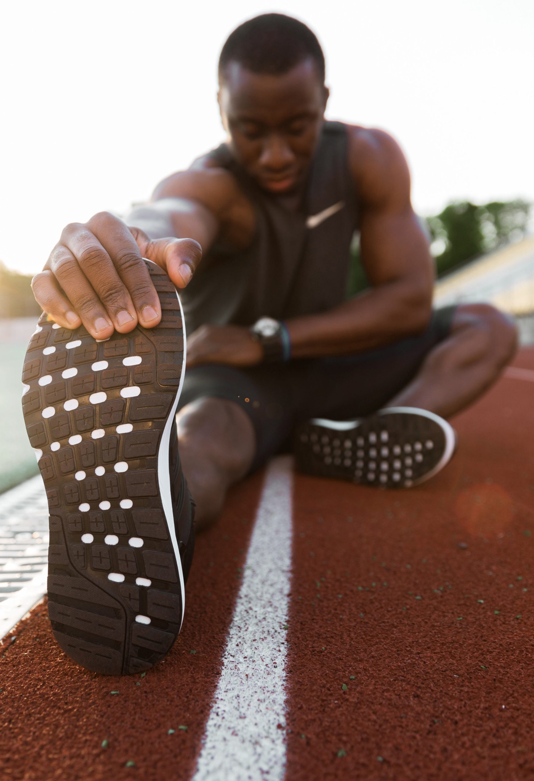 Young concentrated male athlete stretching legs